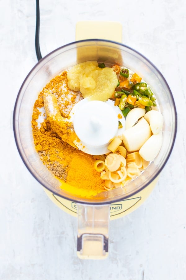 A food processor full of ingredients for a Thai yellow curry paste recipe.