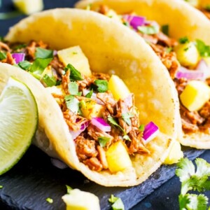 Gluten-free Instant Pot Tacos al Pastor on a serving slate with lime wedges on the side.