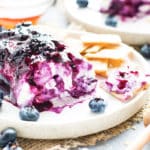 Goat cheese dip recipe on a serving plate with crackers and blueberries.