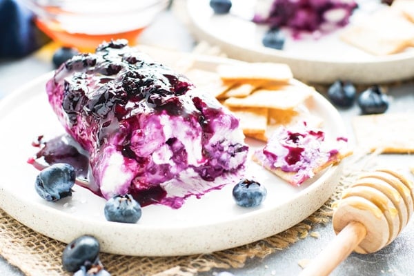 Goat cheese dip recipe on a serving plate with crackers and blueberries.