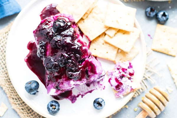 Gluten-free goat cheese log topped with blueberries on a plate.