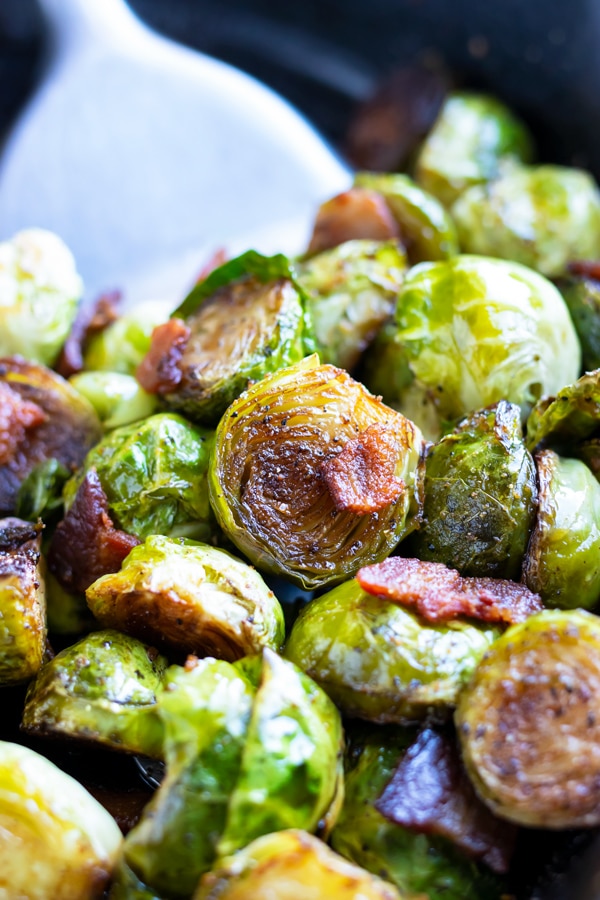Roasted Brussels sprouts in a skillet with bacon pieces.