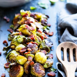 Paleo Brussels sprouts with bacon on a table with a wooden spoon.