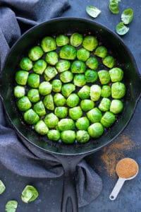 A cast iron skillet full of Brussels sprouts that do not overlap and are placed in a circle for a low-carb side dish.