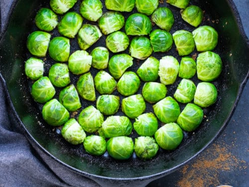 A cast iron skillet full of Brussels sprouts that do not overlap and are placed in a circle for a low-carb side dish.