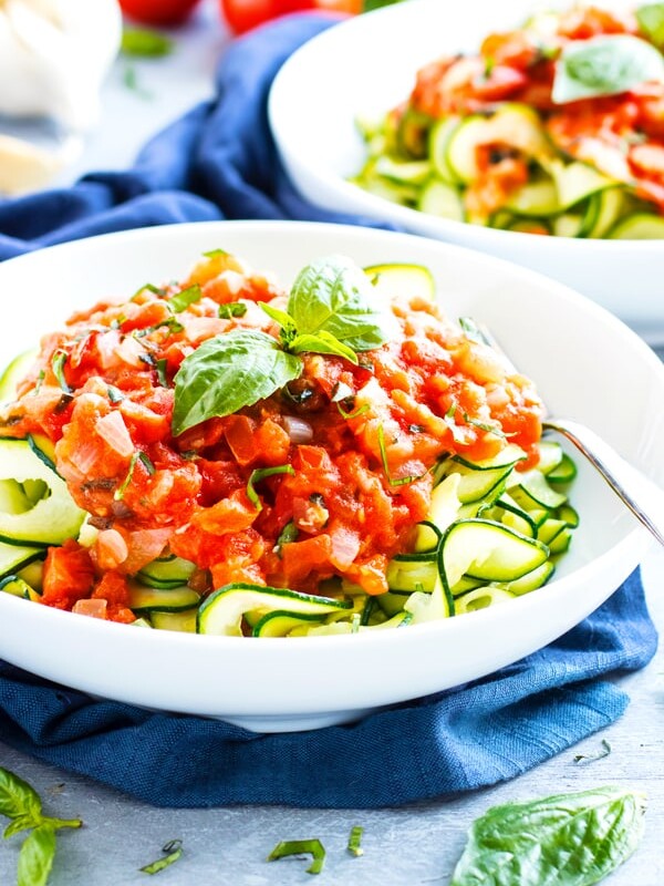 Zucchini noodles with a fresh tomato basil topping in a bowl for lunch.