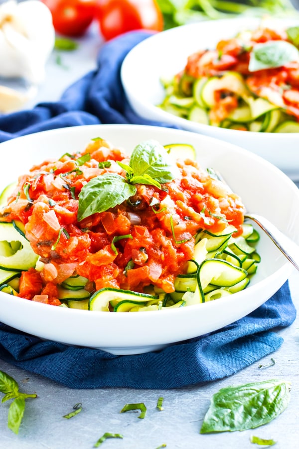Zucchini noodles with a fresh tomato basil topping in a bowl for lunch.