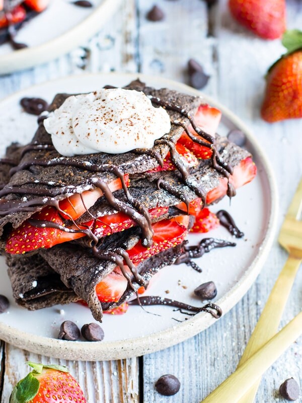 Gluten-free chocolate crepes with sliced strawberries for an easy breakfast.