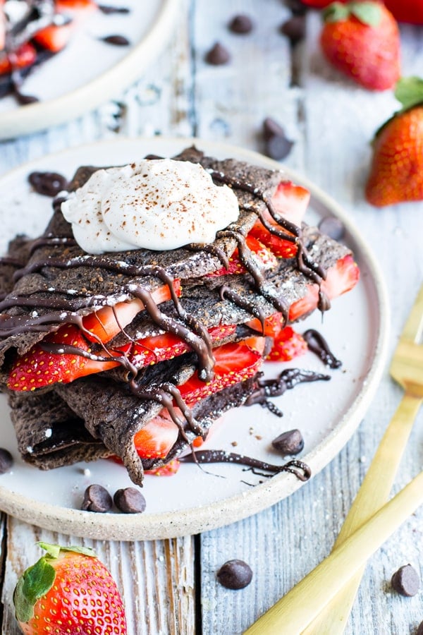 Gluten-free chocolate crepes with sliced strawberries for an easy breakfast.