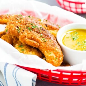 Paleo fried chicken tender recipe in a red basket with honey mustard sauce.