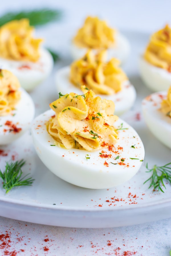 Low carb, keto, and Paleo deviled eggs made with mayonnaise and dill on a white plate.
