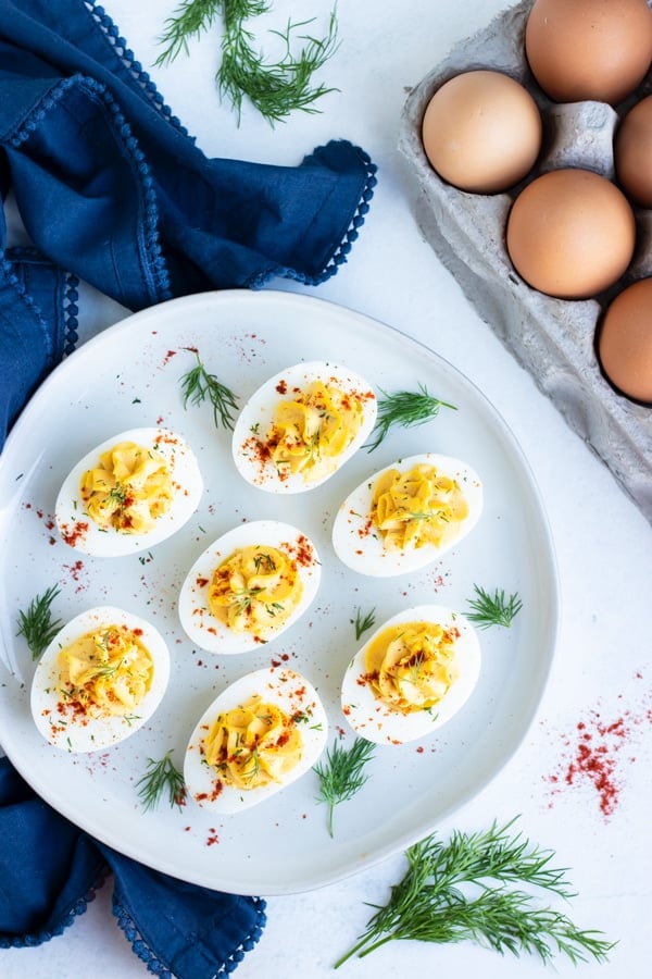 An appetizer platter full of Paleo deviled eggs next to a dozen eggs.