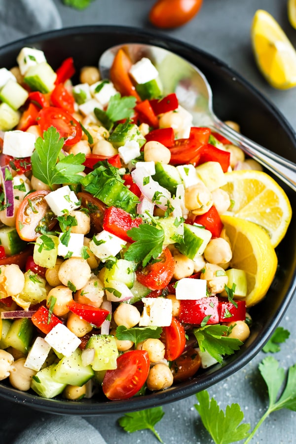 Mediterranean Chickpea Salad in a black bowl with a spoon.