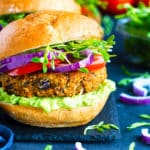 A single gluten-free, Sweet Potato Black Bean Burger with red onions on a slab.