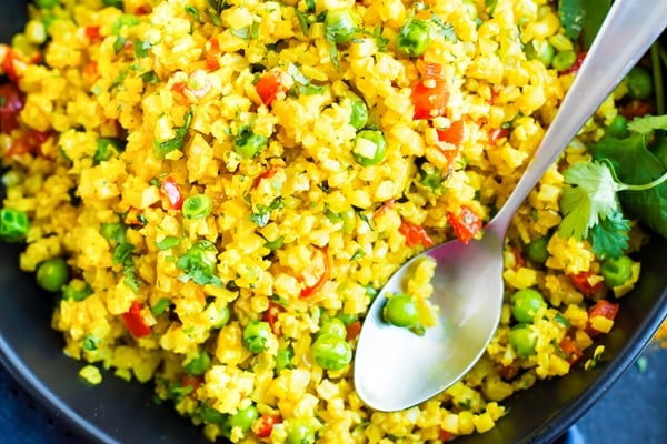A close-up picture of gluten-free curry cauliflower rice with a spoon.