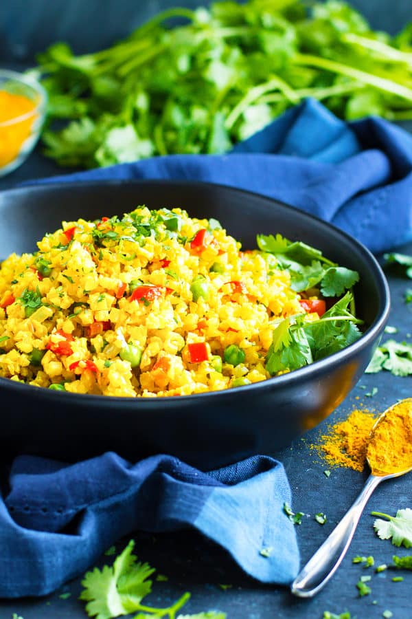 Easy Curry Cauliflower Rice in a bowl on a blue table.