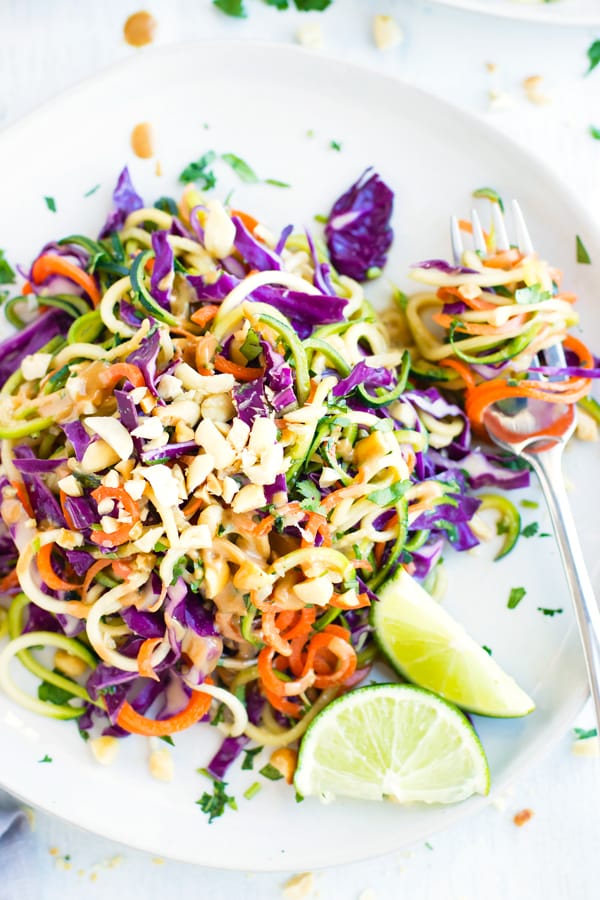 Gluten-free zucchini noodles on a white plate with a fork.