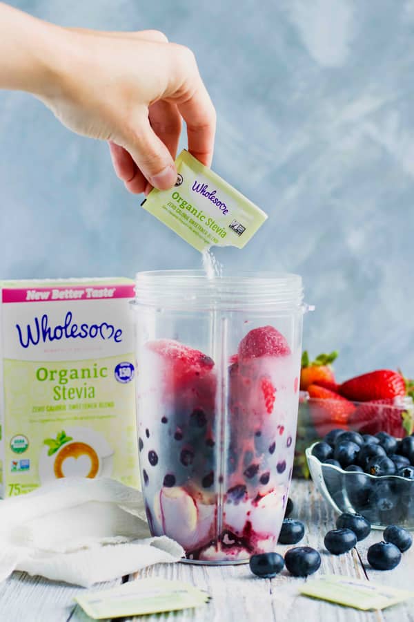 A packet of Wholesome Organic Stevia being poured into a blender with fruit.