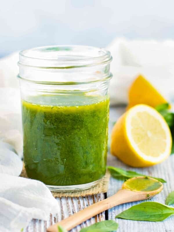 Lemon basil vinaigrette dressing in a mason jar with a wooden spoon next to it.