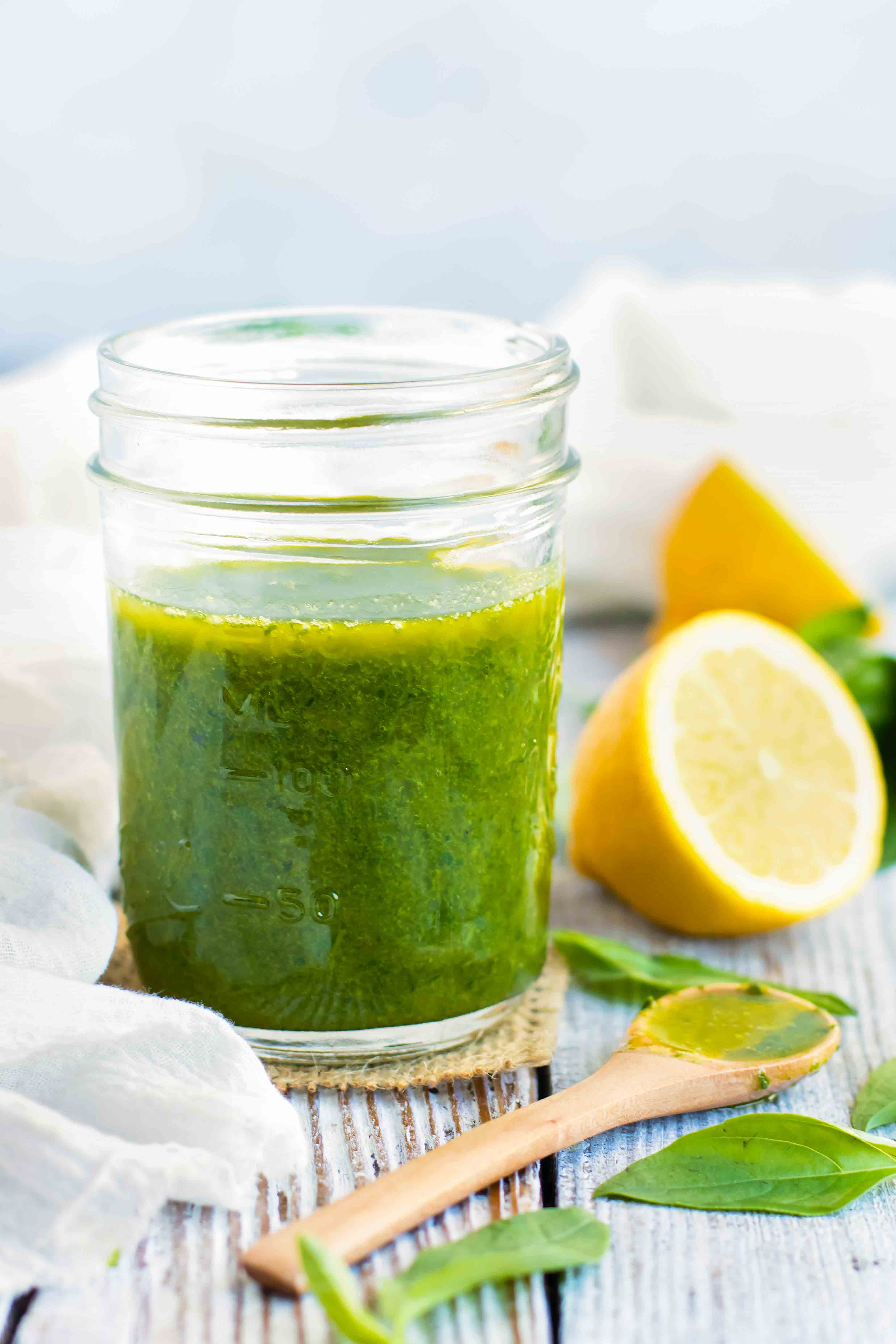 Lemon basil vinaigrette dressing in a mason jar with a wooden spoon next to it.