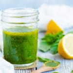 Healthy basil vinaigrette dressing with lemon on a table with a white napkin.