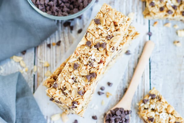 A pile of no bake granola bars on a table with a wooden spoon.