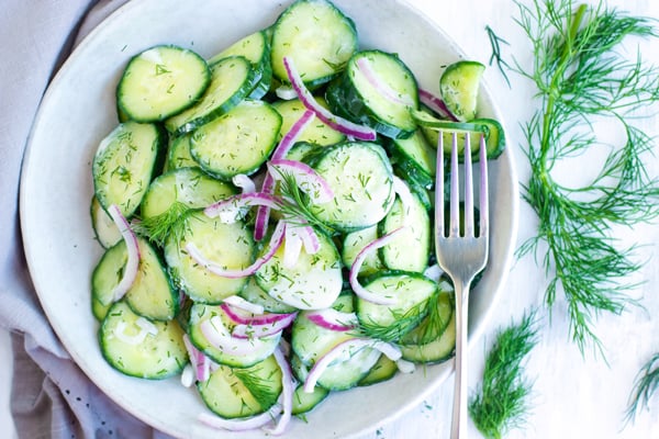 Creamy cucumber salad with red onions in a bowl for lunch.