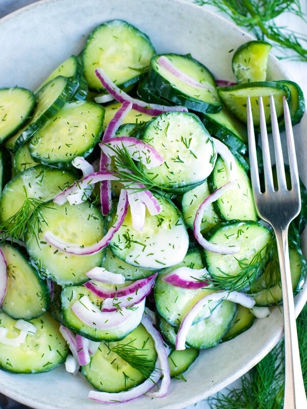 A bowl filled with healthy, gluten-free cucumber dill salad with a fork on the side.