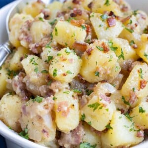 An old-fashioned German potato salad is served in a white bowl for a side dish.
