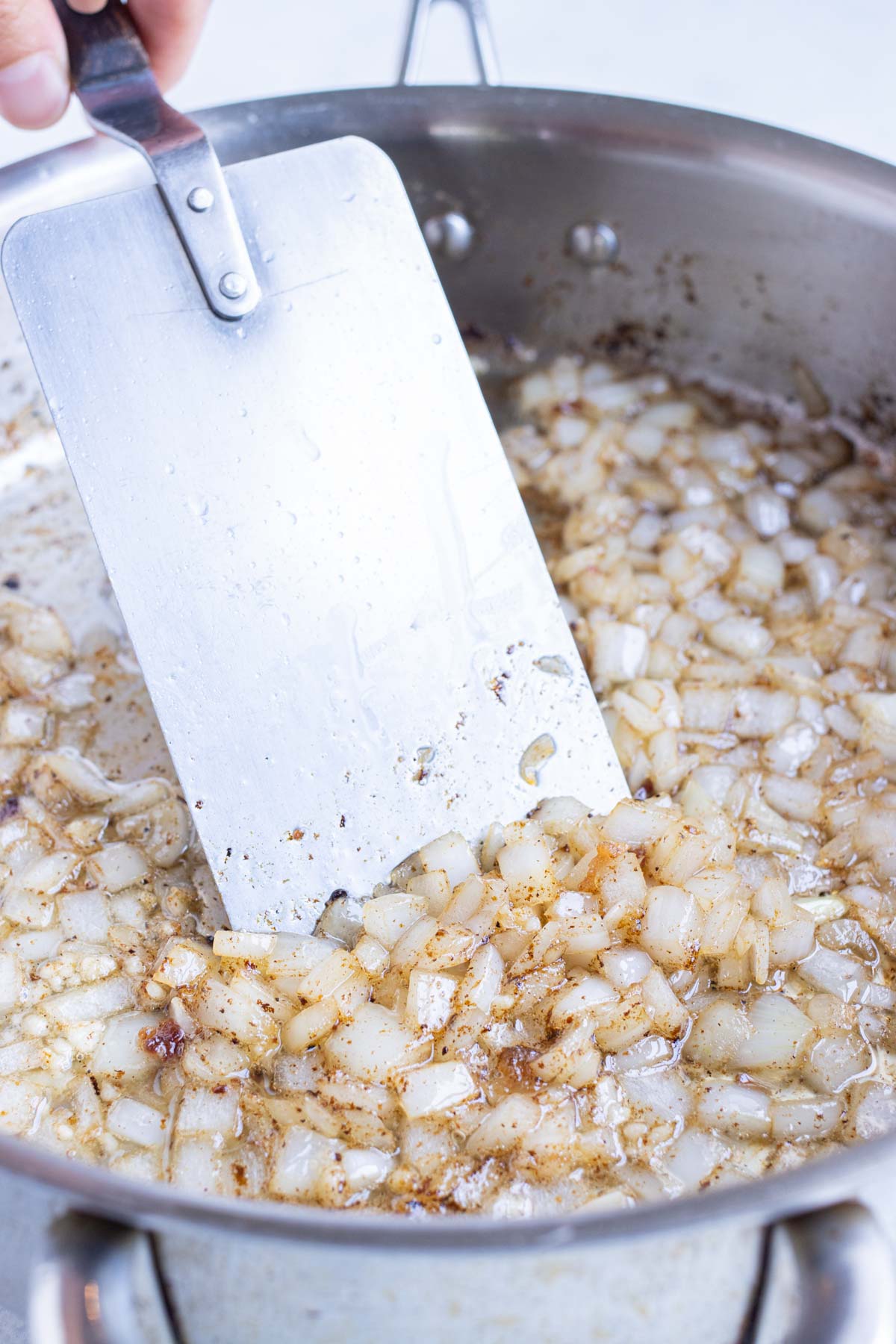 Diced onions are sautéed on the stove.