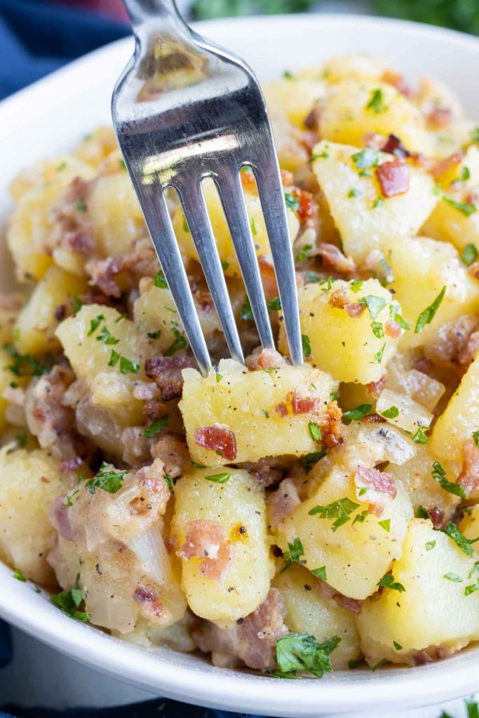 A fork is used to eat warm German potato salad.