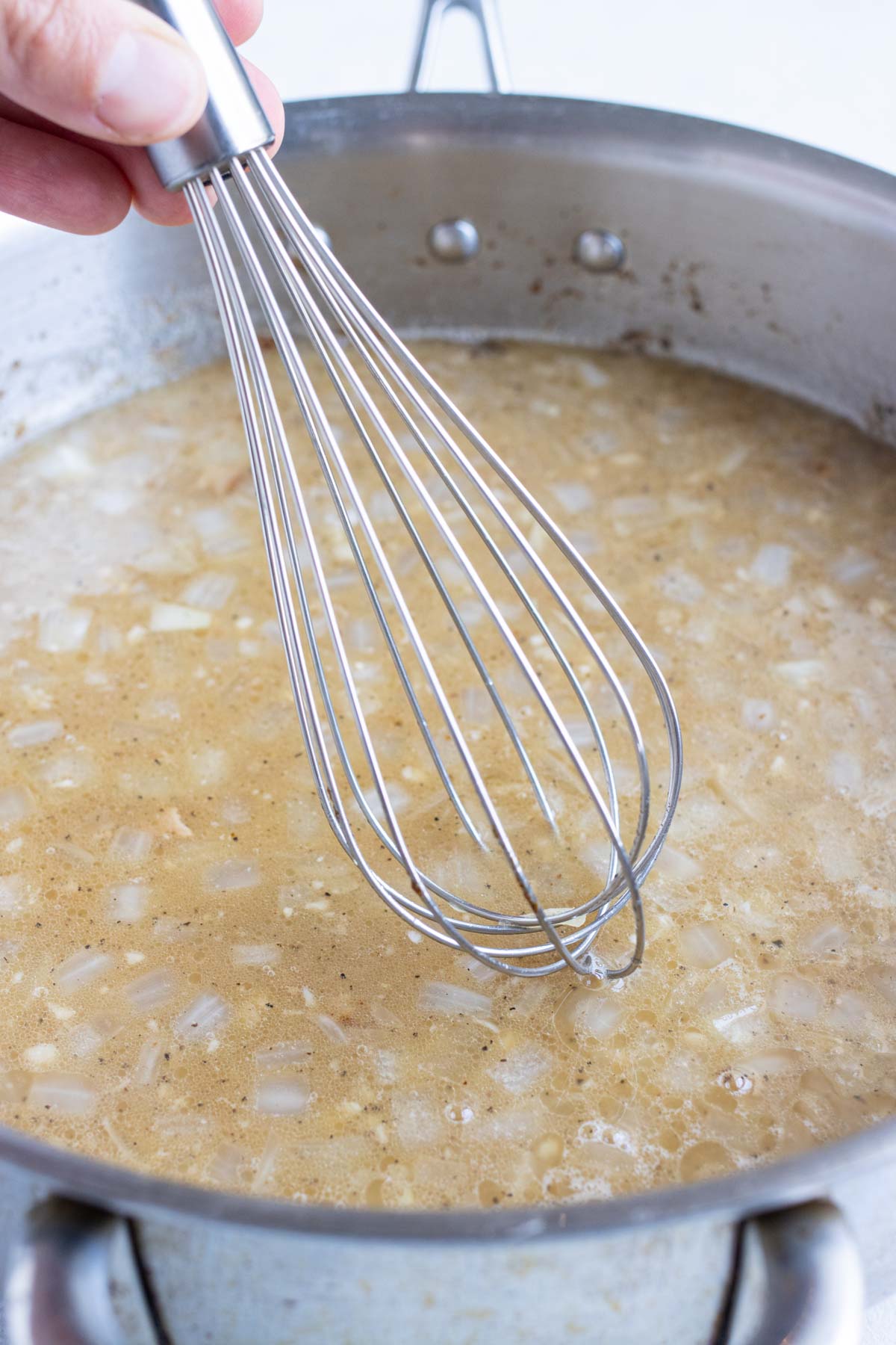 Broth and vinegar are added and whisked together with the onions.