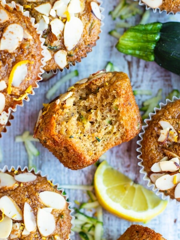 Gluten-free zucchini muffin with a bite inside surrounded by other muffins.