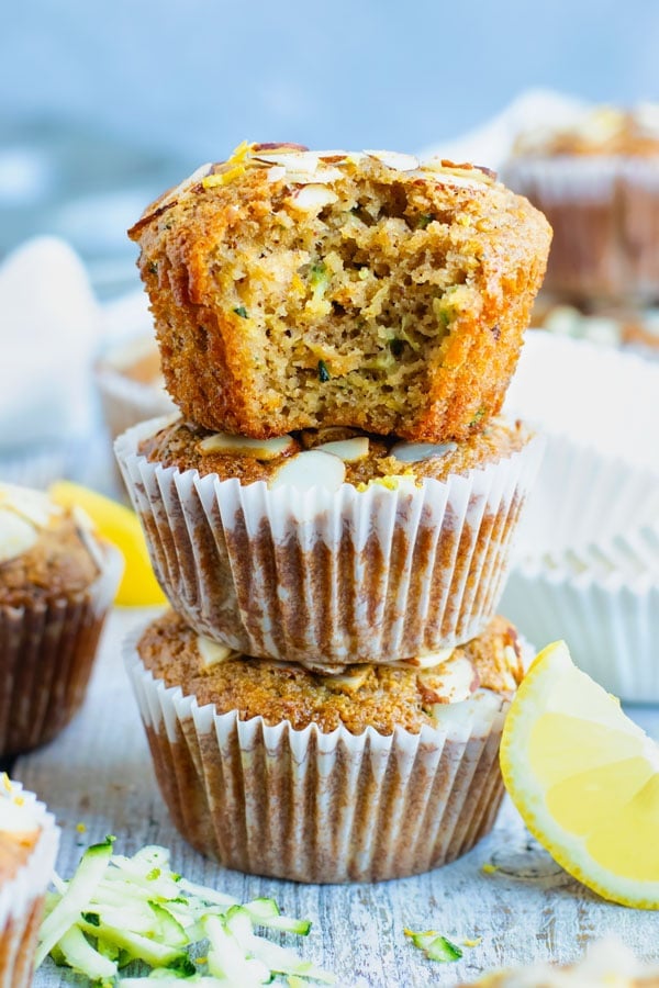 A pile of easy healthy zucchini muffins on a table with a lemon slice.