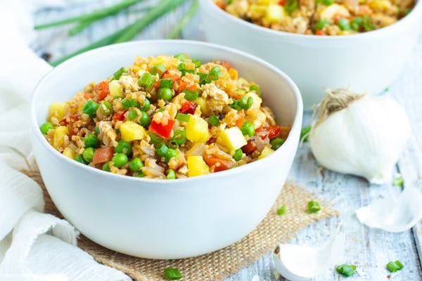 A white bowl of gluten-free cauliflower fried rice with pineapples.