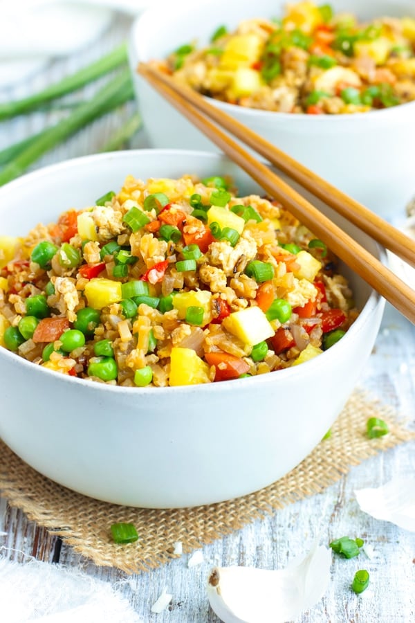 Easy Pineapple Cauliflower Fried Rice in a white bowl with chopsticks on the side.