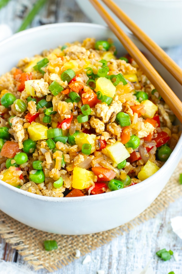 A bowl of Easy Pineapple Cauliflower Fried Rice with chopsticks for dinner.