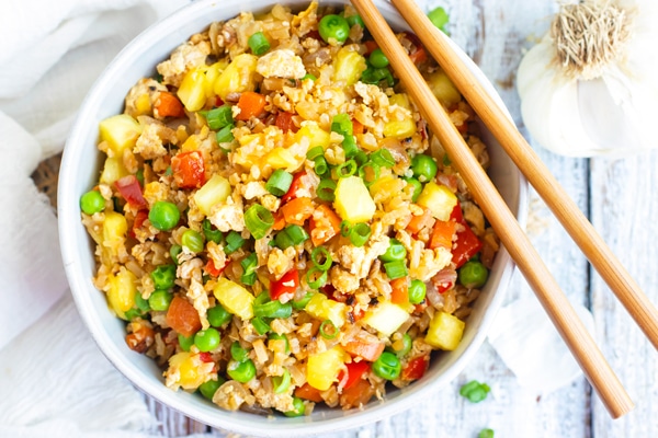 Easy pineapple fried rice in a white bowl with chopsticks.
