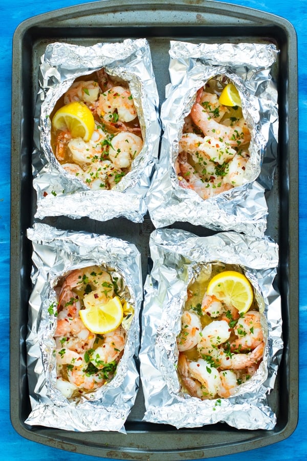 Gluten-free baked shrimp scampi in foil packets on a baking sheet.