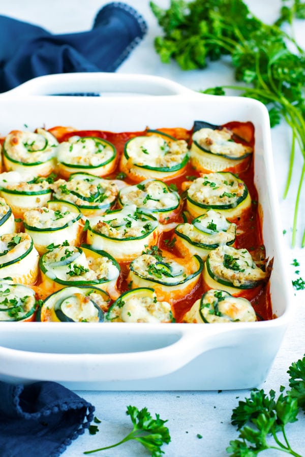 Easy zucchini lasagna roll-ups in a white dish with a blue napkin.