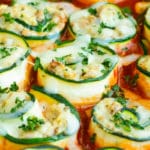 Easy zucchini lasagna roll-ups in red sauce garnished with herbs.