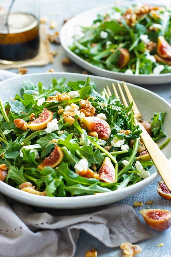 Gluten-free fig salad with arugula and goat cheese in a bowl.