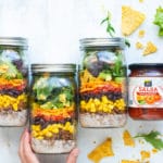 Easy healthy taco salad in mason jars with a jar of salsa on the side.