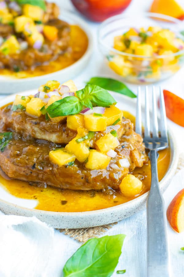 Easy Instant Pot pork chops topped with peach salsa on a white plate.