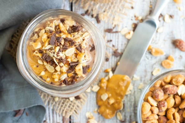 Healthy overnight oats in a jar with a knife dipped in peanut butter.