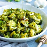 Gluten-free oven roasted broccoli recipe in a white bowl drizzled with a tangy sauce.