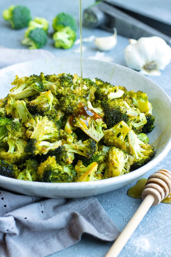 Gluten-free oven roasted broccoli recipe in a white bowl drizzled with a tangy sauce.