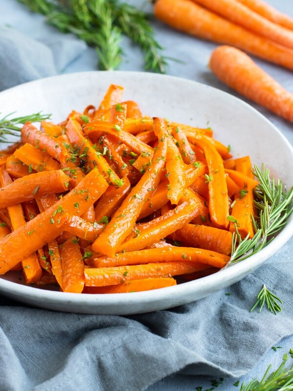 Roasted carrots in a white bowl with a gray napkin.
