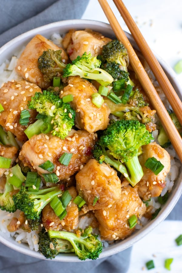 A white bowl full of chicken broccoli stir-fry with rice.