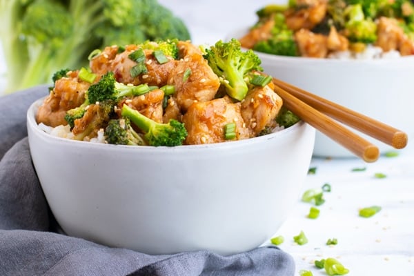 Chicken broccoli stir-fry in a white bowl on a white table.